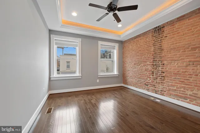 a view of empty room with wooden floor and fan