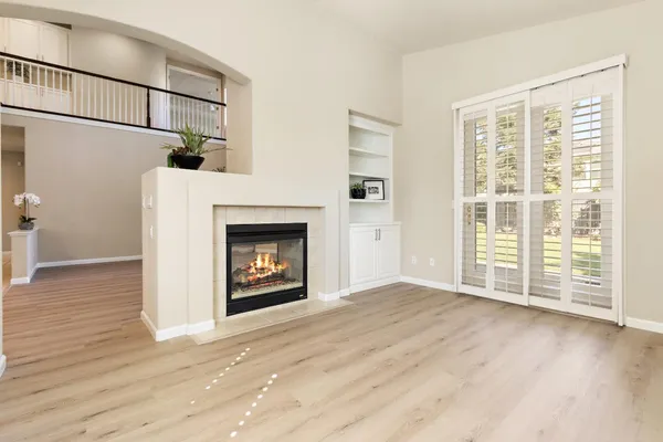 a view of an empty room with a kitchen and a fireplace