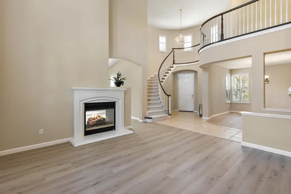 a view of an empty room with wooden floor fireplace and a window