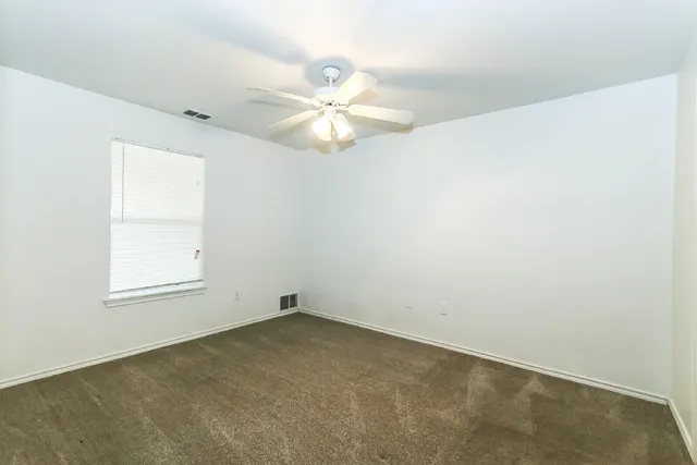 an empty room with a window and a fan