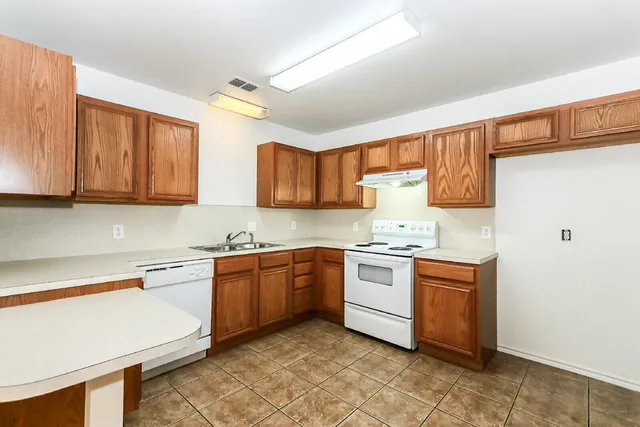 a kitchen with stainless steel appliances granite countertop stove top oven a sink dishwasher and a refrigerator