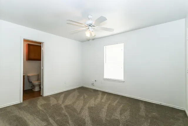 an empty room with a window and a fan