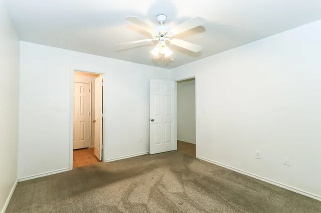 an empty room with a ceiling fan and a window