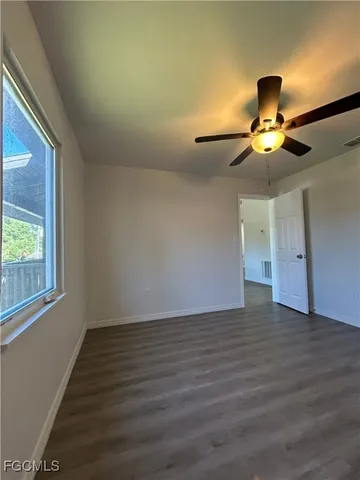 an empty room with wooden floor fan and windows