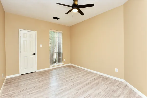 a view of empty room with wooden floor and fan