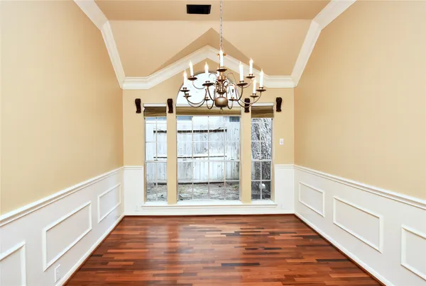 a view of a hallway with wooden floor and chandelier