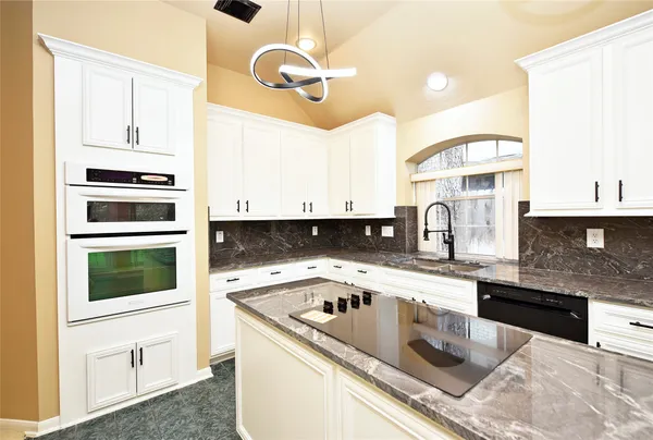 a kitchen with stainless steel appliances granite countertop a sink a stove and cabinets