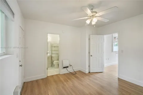an empty room with wooden floor and fan