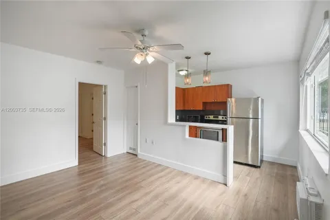 a view of a kitchen with wooden floor a refrigerator and a window