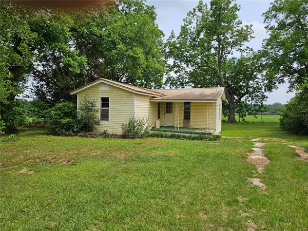 a view of a yard in front of a house with large trees