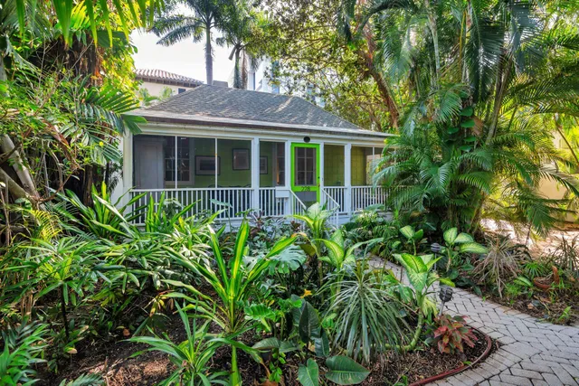 a view of a house with potted plants and large trees