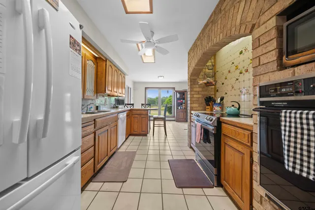 a large kitchen with stainless steel appliances granite countertop a stove top oven a sink dishwasher a dining table and chairs with wooden floor