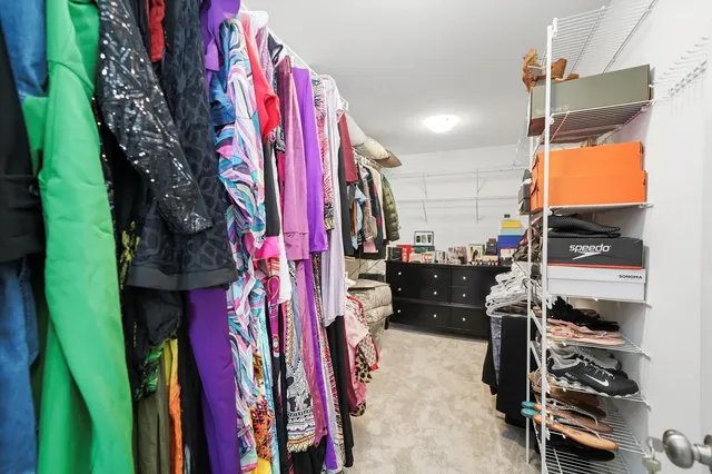 a view of walk in closet with clothes and shoes