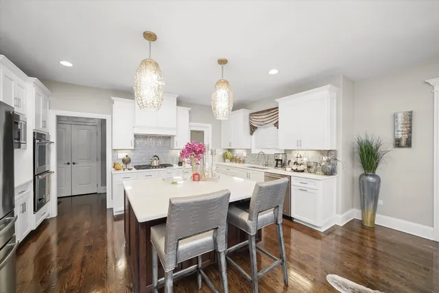 a kitchen with a dining table chairs stainless steel appliances and cabinets