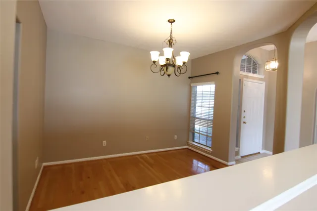 a view of a livingroom with a chandelier fan and kitchen view
