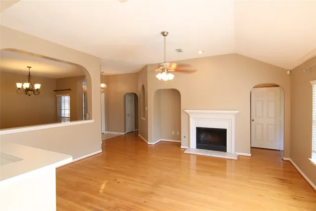 a view of an empty room with chandelier and fireplace