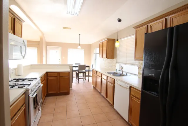 a kitchen with stainless steel appliances granite countertop a refrigerator a stove a sink and a microwave