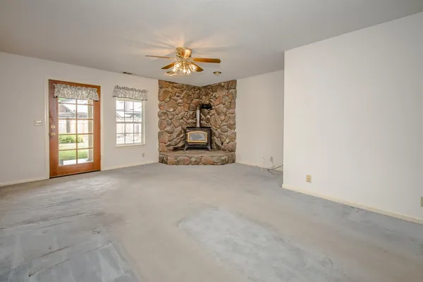 an empty room with windows and chandelier fan
