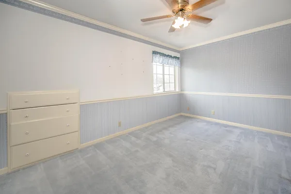an empty room with chandelier fan and windows