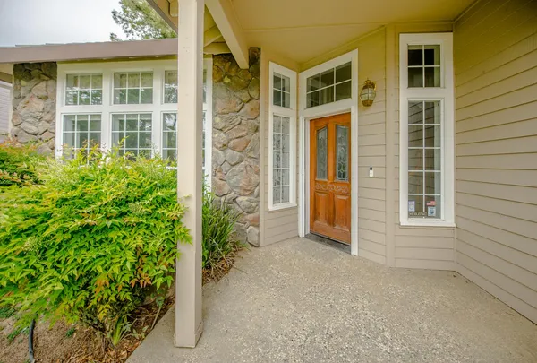 front view of a brick house with a large window and potted plants