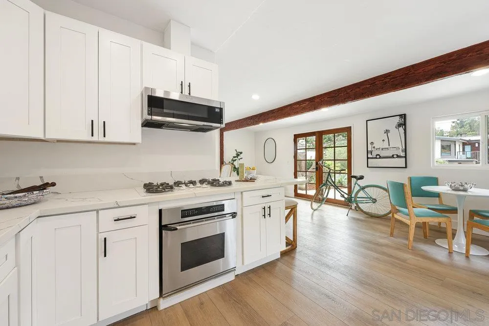 720 Valley Avenue Solana Beach, CA 92075 - Photo 4 of 12 a kitchen with stainless steel appliances granite countertop a stove and white cabinets with wooden floor