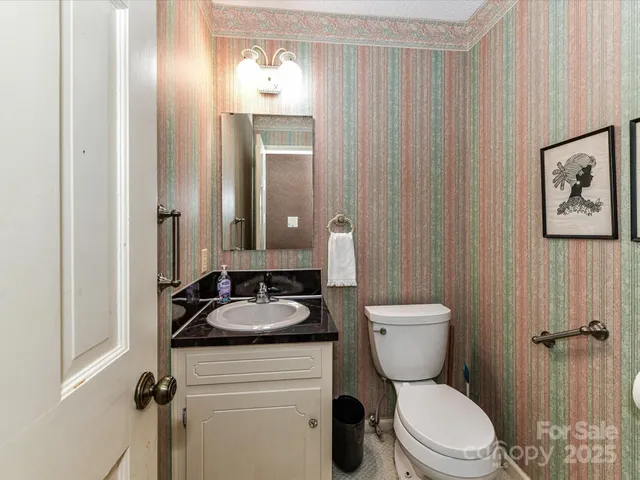 a bathroom with a granite countertop toilet a sink and a mirror