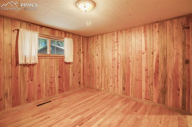 4980 Dodd Road Cascade, CO 80809 - Photo 36 of 48 3rd bedroom with wooden walls and light hardwood flooring