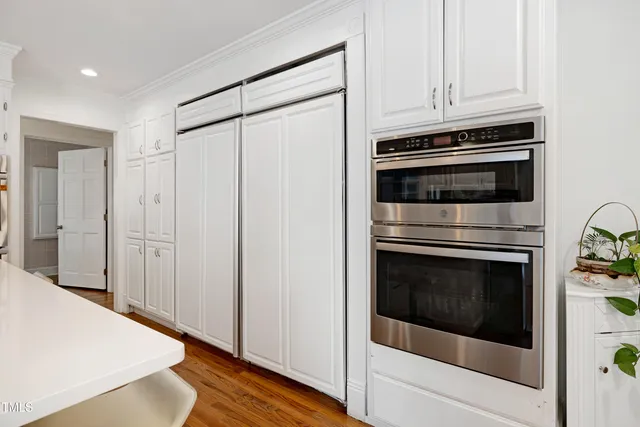 a kitchen with stainless steel appliances white cabinets and a wooden floor