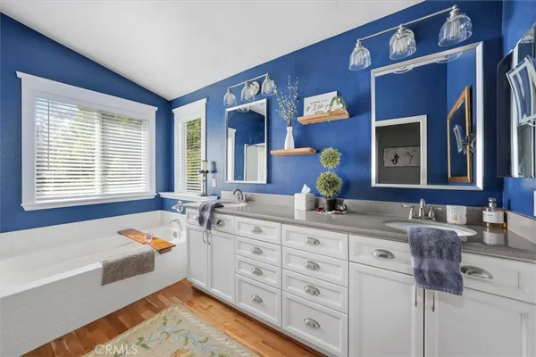 a bathroom with a tub double sink window and mirror