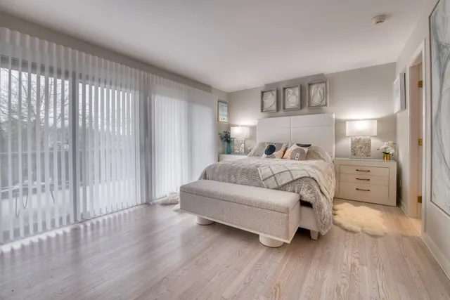 a bedroom with a bed lamp and a large window