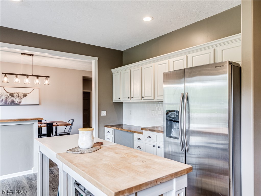 6573 Boneta Road Medina, OH 44256 - Photo 12 of 38 Kitchen featuring tasteful backsplash, stainless steel refrigerator with ice dispenser, wood-type flooring, a kitchen island, and white cabinetry