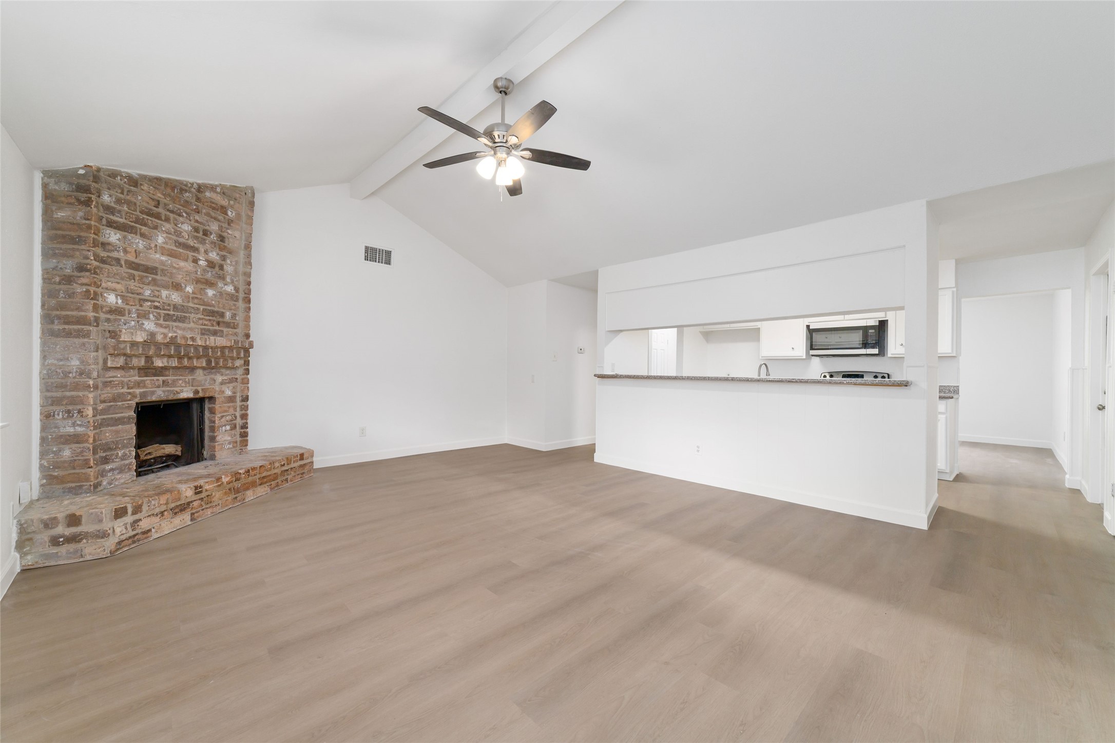 5023 Monteith Drive Spring, TX 77373 - Photo 7 of 20 Open and inviting living space with vaulted ceilings and a ceiling fan, flowing naturally into the kitchen through a wide pass-through for a bright and connected feel.