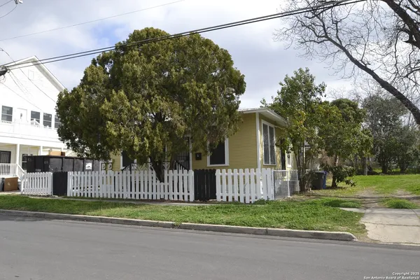 a view of a house with a small yard and wooden fence