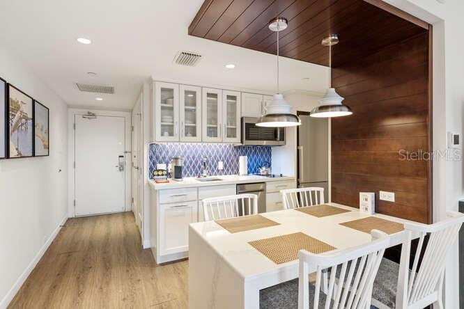 250 Sands Point Road, Unit 5203 Longboat Key, FL 34228 - Photo 9 of 32 a kitchen with a table chairs stove and cabinets