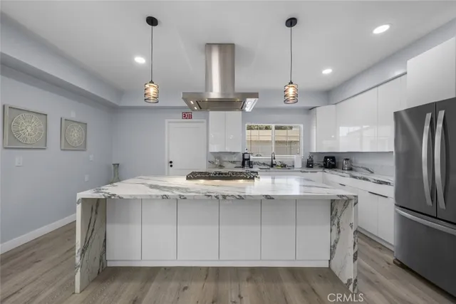 a kitchen with stainless steel appliances granite countertop a sink a stove a refrigerator and island with wooden floor