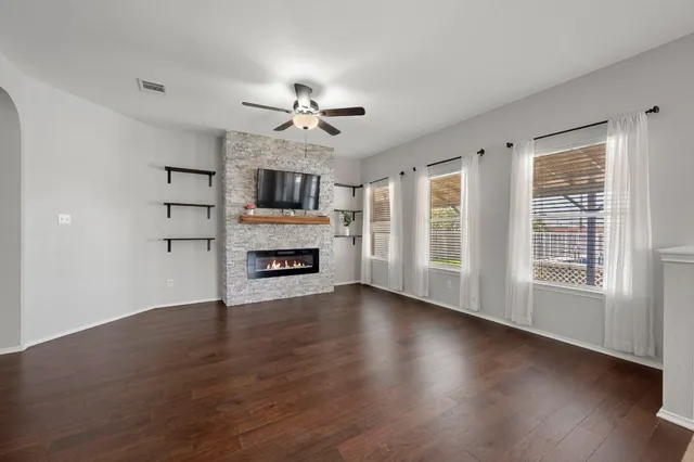 a view of a livingroom with a fireplace a ceiling fan and windows