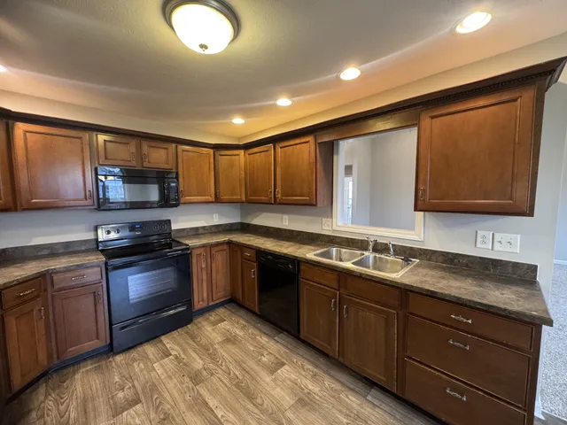 a kitchen with stainless steel appliances granite countertop wooden cabinets a stove top oven a sink and dishwasher