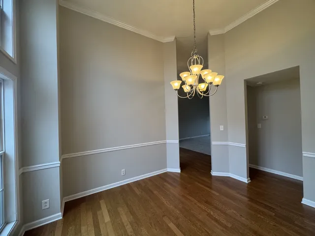 a front view of a dining room with wooden floor chandelier and entryway