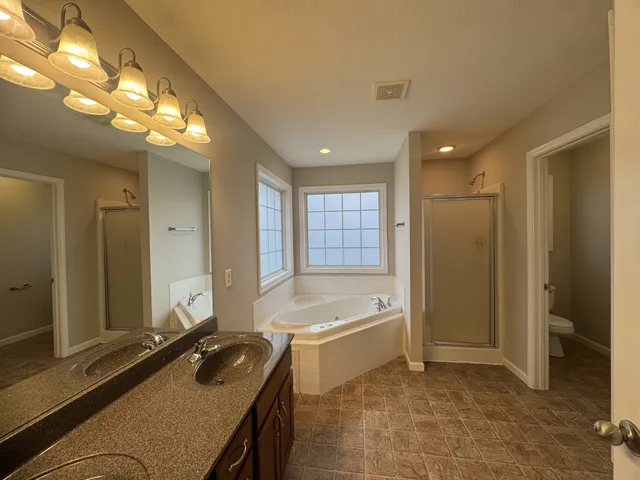 a bathroom with a granite countertop sink and a tub