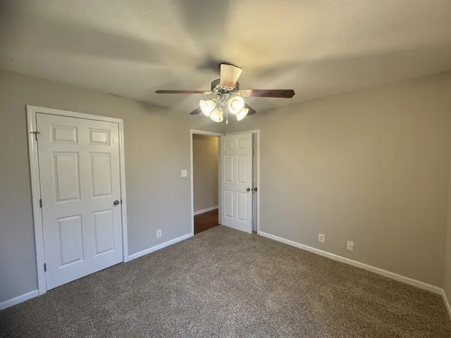 an empty room with a chandelier fan and windows