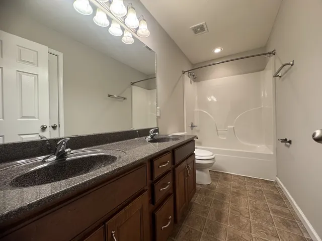 a bathroom with a granite countertop sink a toilet a mirror and shower