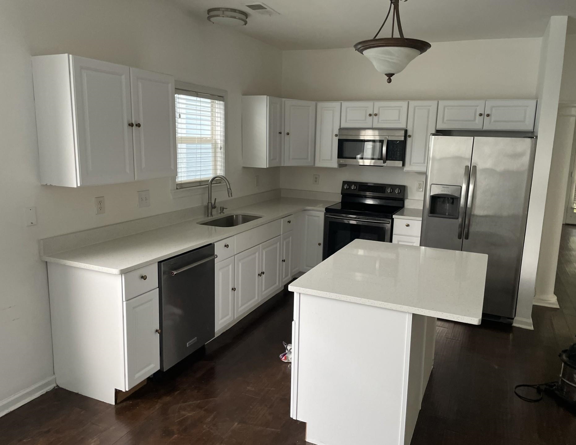 1173 Island Place East Memphis, TN 38103 - Photo 2 of 18 Kitchen with appliances with stainless steel finishes, dark wood finished floors, white cabinets, light countertops, and a kitchen island
