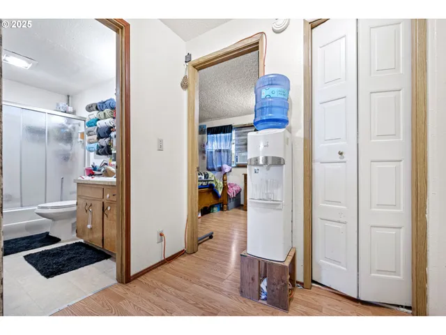 a view of a hallway with wooden floor and a bathroom with a sink