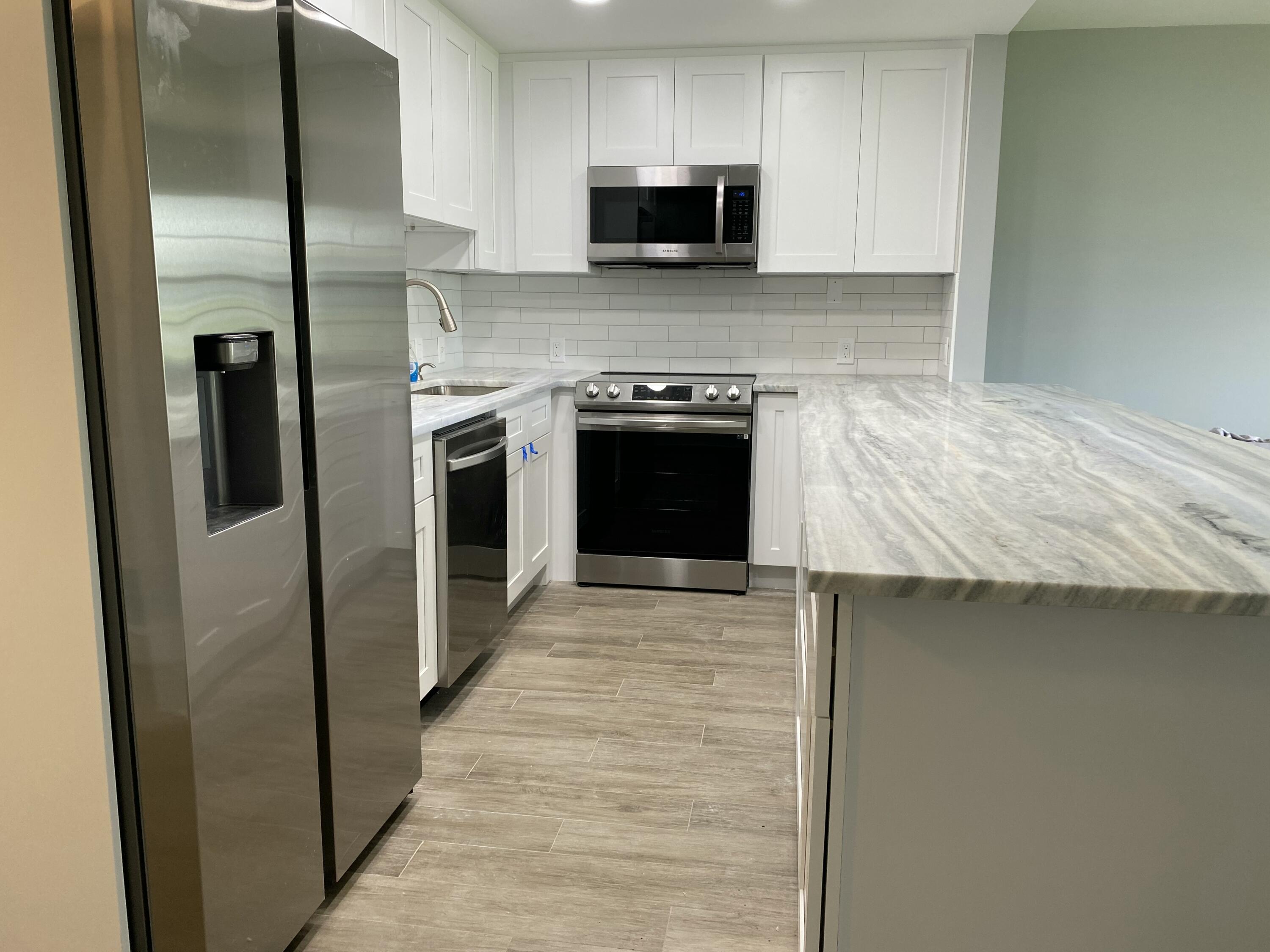 342 Mansfield Drive, Unit I Boca Raton, FL 33434 - Photo 3 of 17 a kitchen with stainless steel appliances granite countertop a stove top oven a sink and a refrigerator