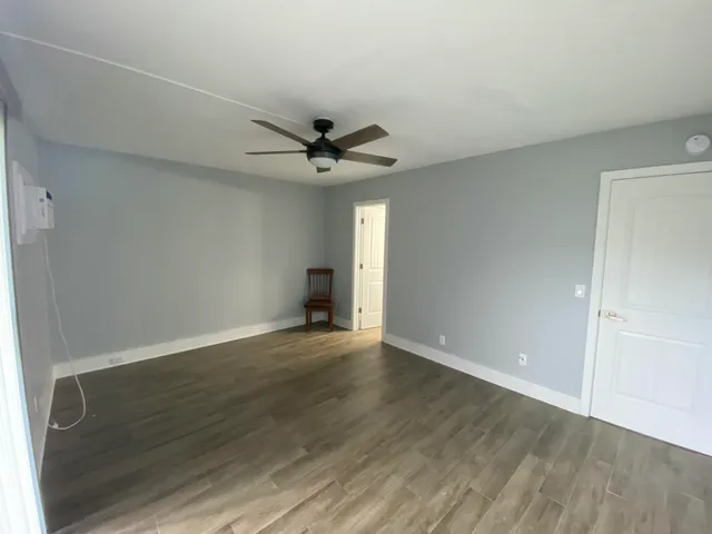 an empty room with wooden floor and a ceiling fan
