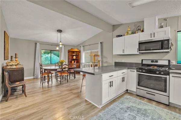 a open kitchen with stainless steel appliances granite countertop a stove top oven a sink dishwasher a dining table and chairs with wooden floor