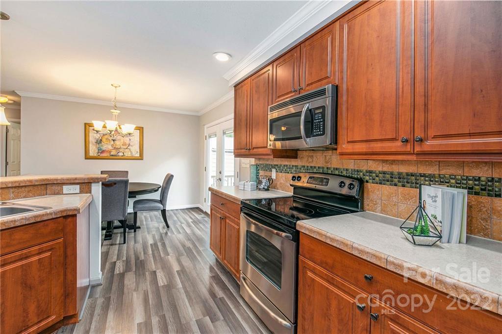 6130 Long Ferry Road Salisbury, NC 28146 - Photo 14 of 32 a kitchen with stainless steel appliances granite countertop wooden cabinets a stove top oven a sink and dishwasher a dining table with wooden floor