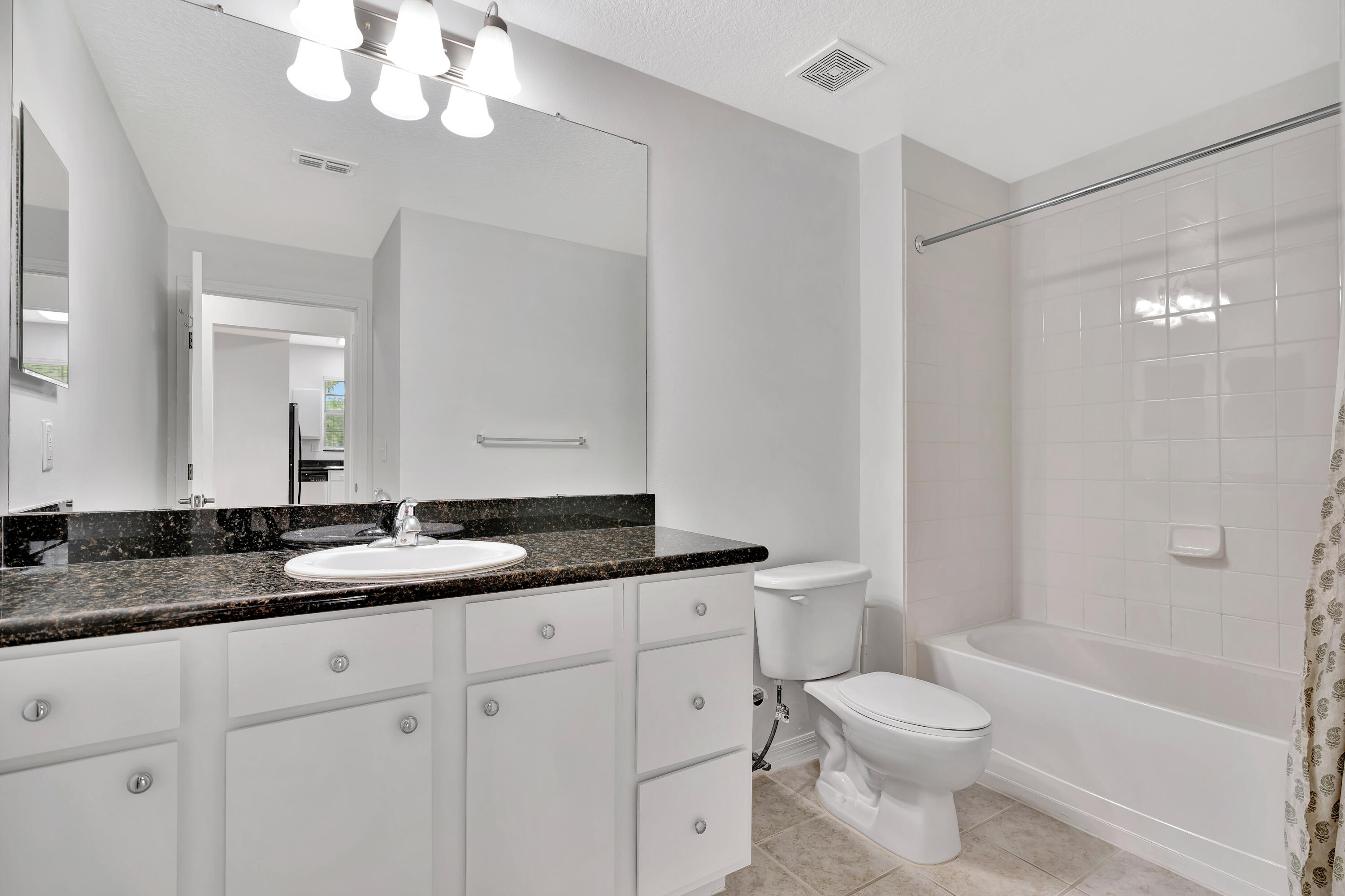 1561 Southeast Pomeroy Street Stuart, FL 34997 - Photo 15 of 25 a bathroom with a granite countertop sink a toilet and bathtub