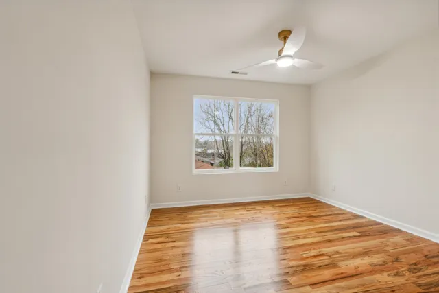 a view of an empty room with wooden floor and a window