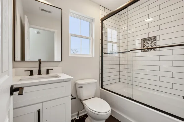 a bathroom with a toilet a sink a mirror and shower